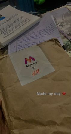 a brown paper bag sitting on top of a table next to a pile of papers