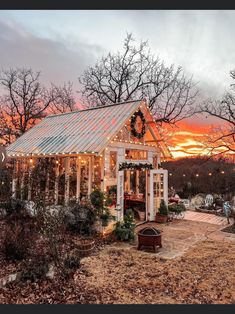 a small white house sitting in the middle of a field with lights hanging from it's roof