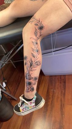 a woman's leg with flowers on it and her foot in the middle of the floor