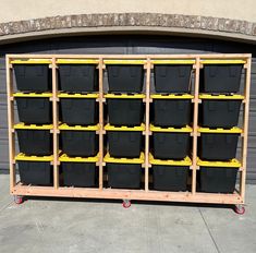 a large wooden rack filled with black and yellow bins next to a garage door