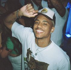 a man in a white shirt and hat at a party with other people around him