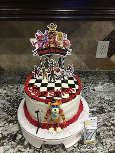 a cake decorated with cartoon characters on top of a marble counter next to a sign