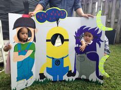 two children are standing in front of a cardboard cut out of despicable characters