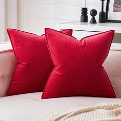 two red pillows sitting on top of a white couch