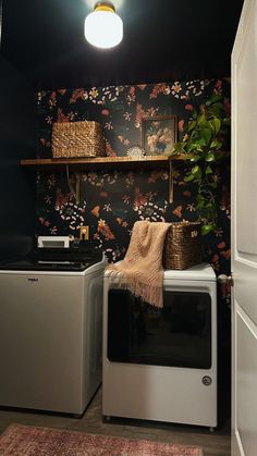 a washer and dryer in a small room with floral wallpaper on the walls