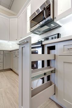 a kitchen with white cabinets and stainless steel stove top oven in the middle of it