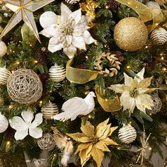 a christmas tree decorated with gold and white balls, poinsettis and ornaments