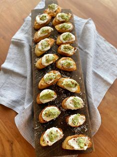 small appetizers are lined up on a wooden board with napkins next to them