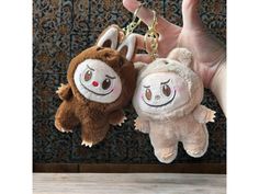 two stuffed animals are hanging from a keychain in someone's left hand