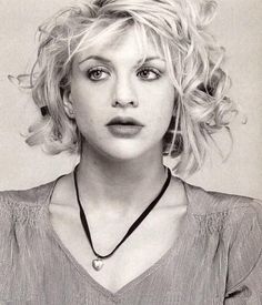 a black and white photo of a woman with blonde hair wearing a necklace on her neck