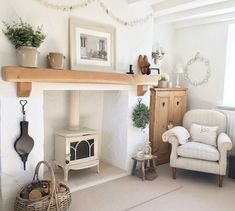 a living room with a fireplace, chair and potted plants on the mantel