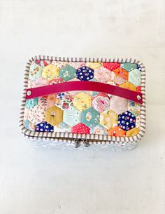 a colorful patchwork purse with pink ribbon on it's side and an empty wallet in the middle