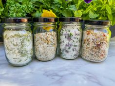 four jars filled with different types of herbs