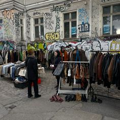 a man standing in front of a clothing rack filled with jackets and shirts on display