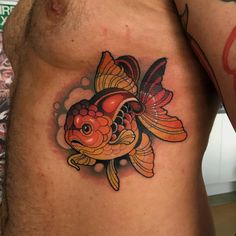 a close up of a man's chest with a goldfish tattoo on it