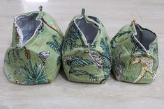 three pairs of baby shoes are sitting on the floor, one is green and the other has giraffes