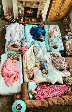 several people sleeping on mattresses in front of a fire place with blankets around them