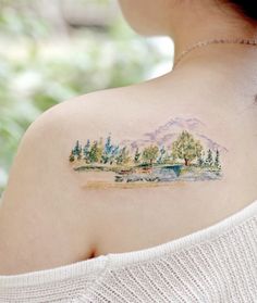 a woman with a tattoo on her back shoulder and trees in the water behind her