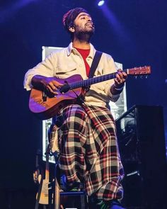 a man sitting on top of a chair holding a guitar