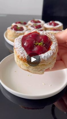 a person is holding up a pastry with jelly on top and powdered sugar on the bottom