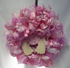 a pink wreath with white polka dots and a bird on it is hanging from the wall