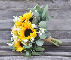 a bouquet of sunflowers and greenery on a bench