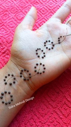 a person's hand with small black beads on it and the word love written in arabic