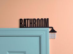 a bathroom sign on the wall above a blue door with earrings hanging from it's hooks