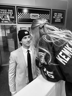 a man in a suit and tie standing next to a woman wearing a hockey jersey