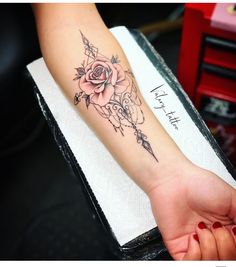 a woman's arm with a rose and arrow tattoo on the left side of her arm