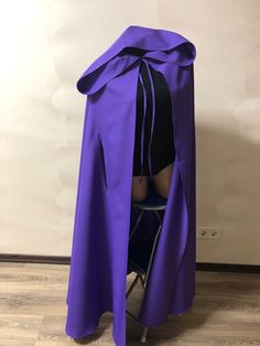 a woman in a purple cape sitting on a chair