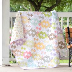 a quilt is hanging on the back of a chair in front of a white fence