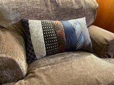 a brown chair with pillows on it and a wooden wall behind the armrests