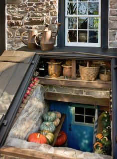 a blue door is open in front of a stone building with pumpkins and gourds