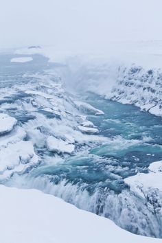 a man standing on top of a snow covered slope next to a river