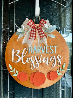 a wooden sign that says harvest blessing hanging on a door with pumpkins and leaves