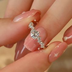 a woman's manicured nails with a diamond ring on her thumb and the tip of her finger