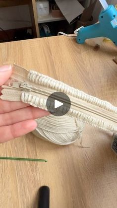 a person is holding a piece of white string on top of a wooden table with scissors