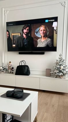 a flat screen tv mounted on the wall in a living room next to a white coffee table