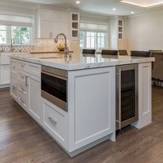 a large kitchen with an island in the middle and white cabinets on both sides is shown