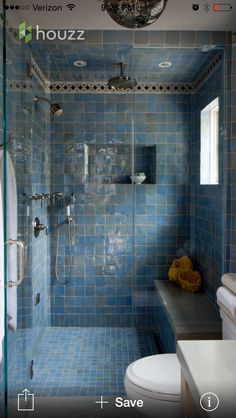 a blue tiled bathroom with a shower, toilet and sink