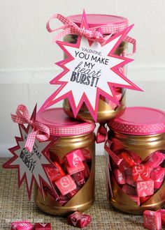 two jars filled with pink and white candies next to a sign that says you make my heart burst