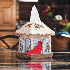 a tissue dispenser with a red cardinal on it sitting on a table