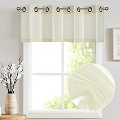 a window with white curtains in front of it and a vase with flowers on the table