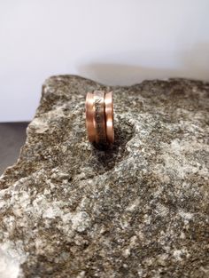 two gold wedding bands sitting on top of a rock with the word love written on it