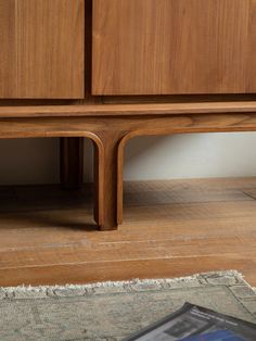 a close up of a wooden cabinet on the floor next to a rug and magazine