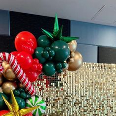 some balloons are hanging in the air near a wall with gold, red and green decorations