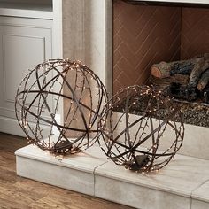 two metal orbs sitting on top of a white marble slab in front of a fireplace