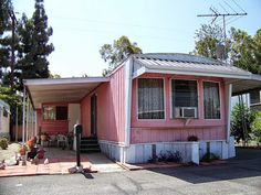 a pink mobile home sits on the corner of a street