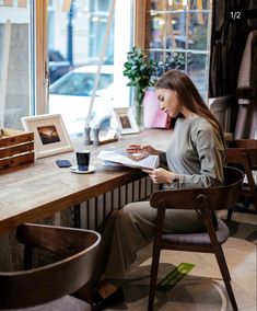 a woman sitting at a table reading a book